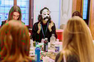 Partecipante con maschera decorata che parla durante l’attività di gruppo.