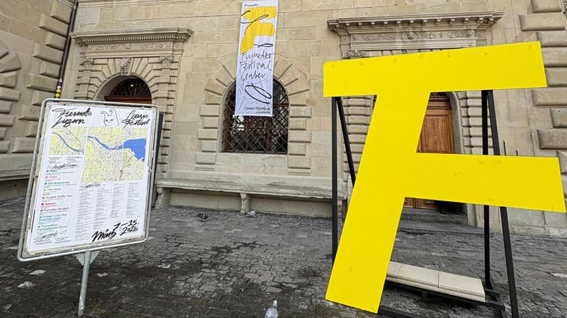Large yellow “F” installation outside a historic building with Fumetto Festival signage and map display.