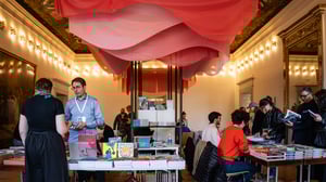 Spazio espositivo di InnovaComix con tavoli di libri e fumetti, visitatori che sfogliano e dialogano con autori ed editori all’interno di una sala storica illuminata.