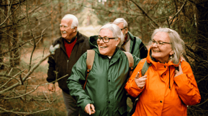 Gruppo di anziani felici mentre fanno un'escursione lungo un sentiero nel bosco in autunno