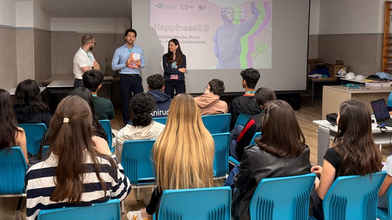 Tre facilitatori posano in aula con una maschera bianca e materiali pronti per il laboratorio HappyLab.