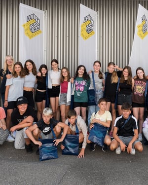 Group photo of students and chaperones during a visit to the Kulturama Museum in Zurich, gathered in front of the museum's flags.