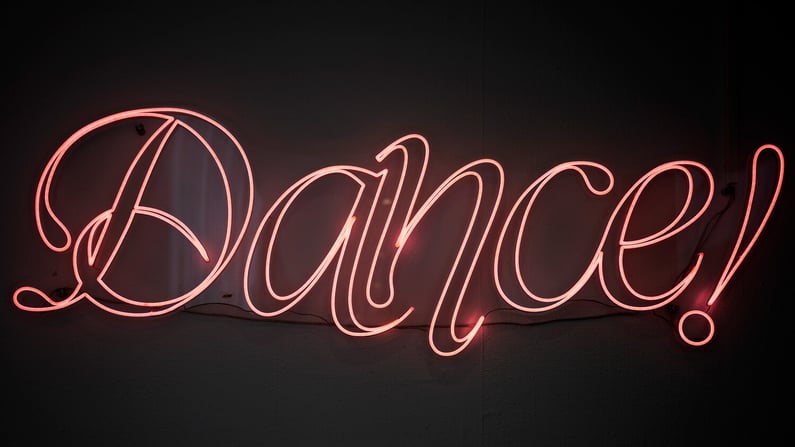 Neon sign with the word ‘Dance!’ glowing in pink