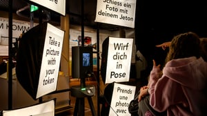 Interactive photo booth with multilingual signs encouraging visitors to strike a pose and take a picture with a token