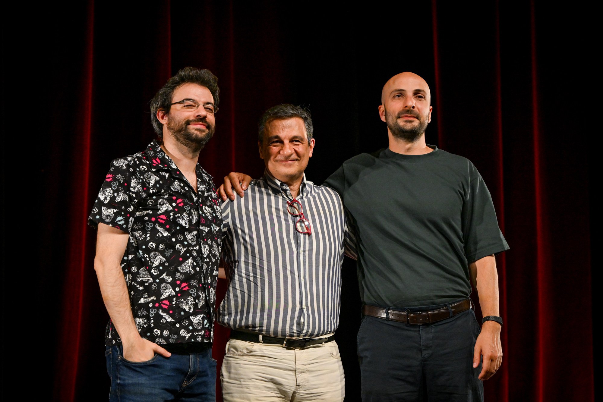 I conduttori del podcast Tintoria posano insieme all'ospite Dario Bressanini palco prima dell'inizio dell'evento a Lugano.