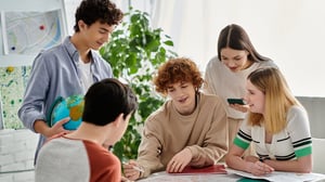 Teenagers sitting around a table smile and do an activity together.