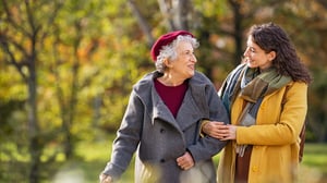 Young woman in a park in winter clothes walking with her elderly grandmother.